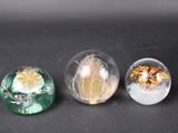 three glass marbles sitting on top of a table next to each other