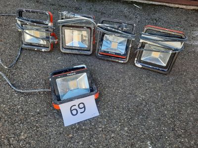 cinq projecteurs posés au sol à côté d'un panneau