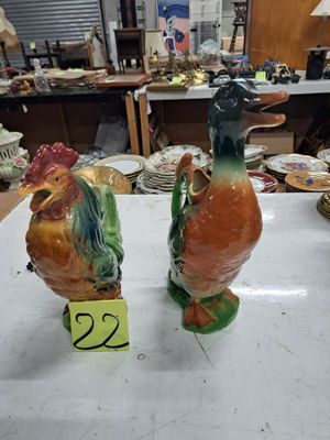 deux figurines de coq en céramique posées sur une table dans une boutique