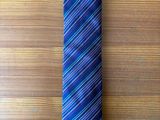 purple and blue striped neck tie on a wooden surface