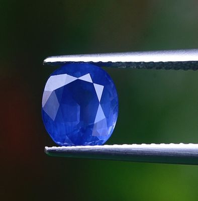 un gros plan d'un saphir bleu tenu par une pince