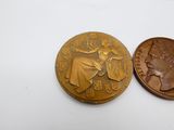 une image représentant une pièce sur laquelle figure une femme, à côté d'un penny