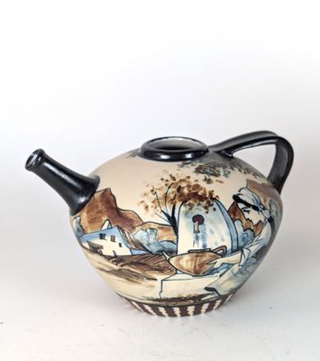 a teapot with a painting on it sitting on a table