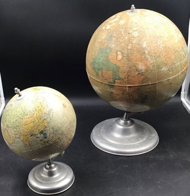 two old globes are sitting on top of each other on a table