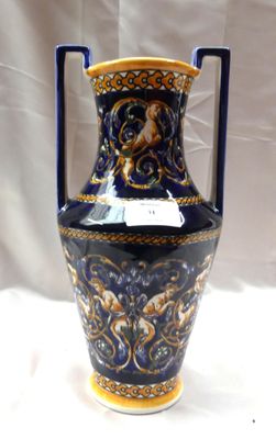 un vase bleu et doré posé sur une table blanche