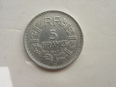 une pièce de 5 francs posée sur une surface blanche