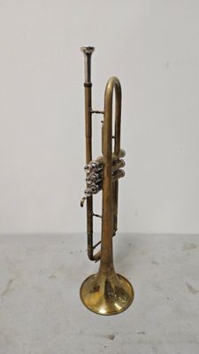 une vieille trompette en laiton posée sur une table blanche