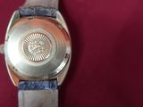 someone is holding a watch on a red surface with a red background