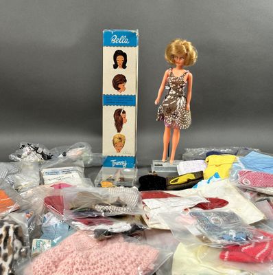 une poupée Barbie assise à côté d'une boîte de vêtements