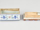 two small ceramic boxes with flowers on them sitting on a table