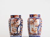 pair of orange and blue vases sitting on a white surface