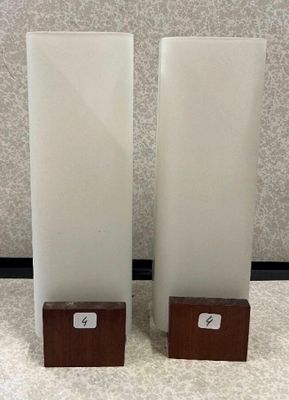 deux grands vases blancs posés sur une table, avec des socles en bois