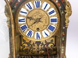 a gold clock with blue and white roman numerals on it