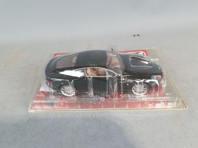 a black toy car in a clear box on a table
