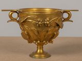 a gold vase with two handles on a table