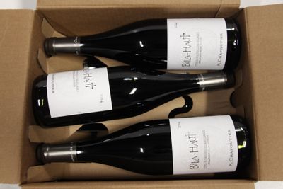 three bottles of wine are in a cardboard box on a table
