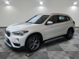 un SUV BMW blanc garé dans un showroom au sol à damier