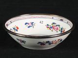 a white bowl with flowers on it on a black surface