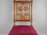 une vieille chaise avec une croix sur le dossier et une assise rouge