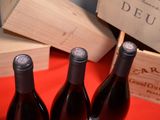 three bottles of red wine sitting next to a wooden box