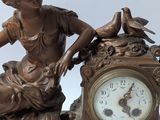 a statue of a woman sitting next to a clock on a table