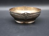 an antique silver bowl on a table with a black background