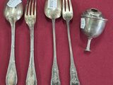 quatre cuillères en argent et une cuillère à café en argent posées sur un napperon rouge