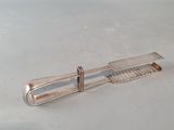 a silver object on a white surface that looks like a comb
