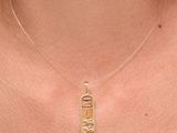a close up of a woman wearing a gold necklace with an egyptian hierole on it