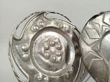 pair of silver plated dishes with decorative designs on white background