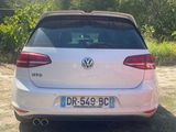 the rear end of a white car parked in a field