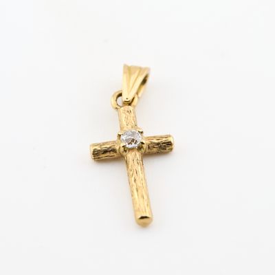 un pendentif en forme de croix en or orné d'un diamant sur fond blanc