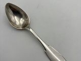 silver spoon on a white surface with a black handle