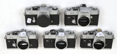 four old cameras are lined up on a white surface