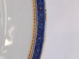 a close up of a blue and white plate with gold trim