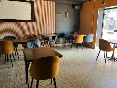 Dans un restaurant doté d'une grande baie vitrée, des tables et des chaises sont alignées.