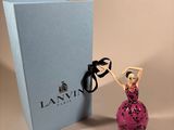 a figurine of a woman in a pink dress next to a blue box