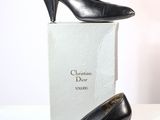 une paire de chaussures noires posée sur une boîte, sur une surface blanche