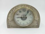 une horloge en argent posée sur une table blanche