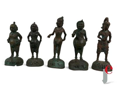 five bronze figurines of women in different poses on a white surface