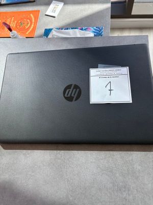 un ordinateur portable HP, sur lequel est collé un autocollant, posé sur une table