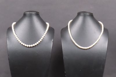 une paire de colliers de perles présentés sur des mannequins posés sur des présentoirs
