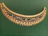 an image of a gold necklace with intricate designs on a green surface