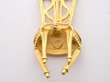 a gold plated pendant with a chair on it