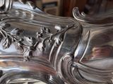 someone is holding a silver plate with a floral design on it