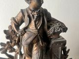 a bronze statue of a boy sitting on a tree stump