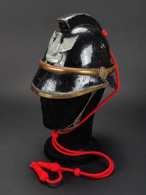 un vieux casque muni d'un cordon rouge, posé sur une tête de mannequin