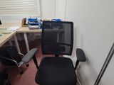 a black office chair sitting in front of a computer desk