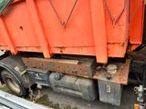 a large orange dump truck that is parked on the side of the road