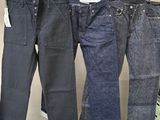 trois paires de jeans suspendues à un portant dans un magasin